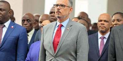 Alix-Didier-Fils-Aime-standing-with-officials-looking-stern-Photo-RL-News-Haiti.jpg