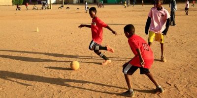 Children-play-football-on-a-dirt-field-at-Al-Iskan-neighborhood-District-95-west-of-Omdurman-Sudan.j.jpeg