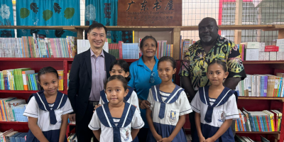 H.E-Weiming-Principal-Tahuniara-and-Minister-Leokana-posing-for-a-photo-in-front-of-the-Books-collection-in-the-schools-library-1.png