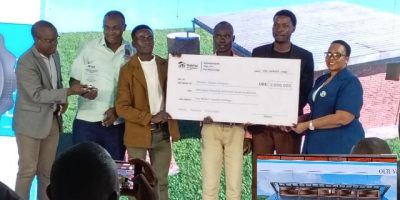 Namuganza-presenting-a-a-dummy-cheque-to.-Kyambogo-engineering-students-for-their-winning-design.png