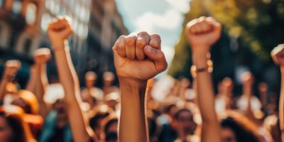 vecteezy_a-group-of-protesters-raise-their-fists-in-the-air_49219012-scaled-1.jpg