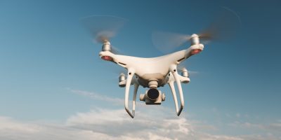 white-drone-hovering-bright-blue-sky-scaled.jpg